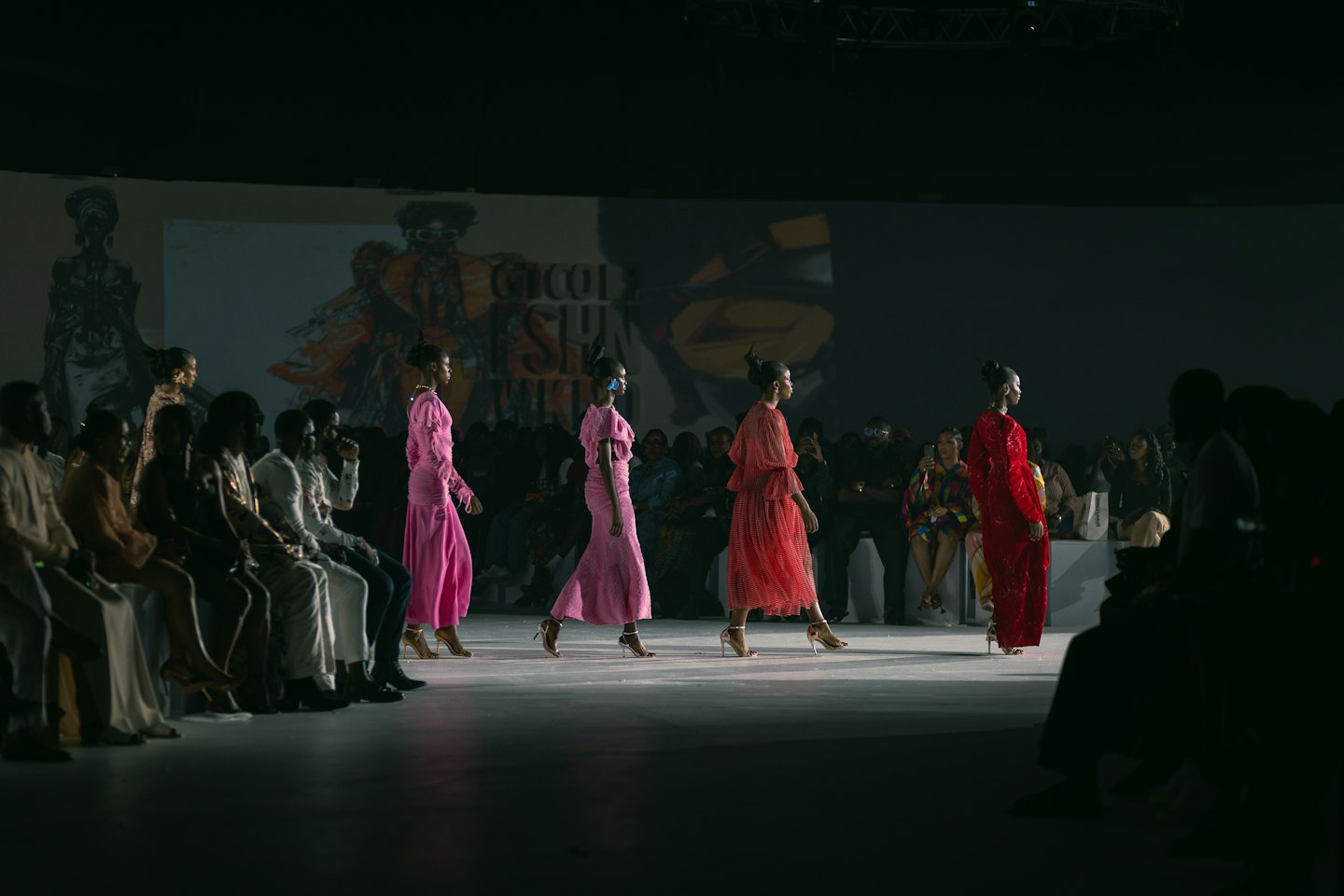 Quattro modelle sfilano in passerella con abiti rosa e rossi firmati.