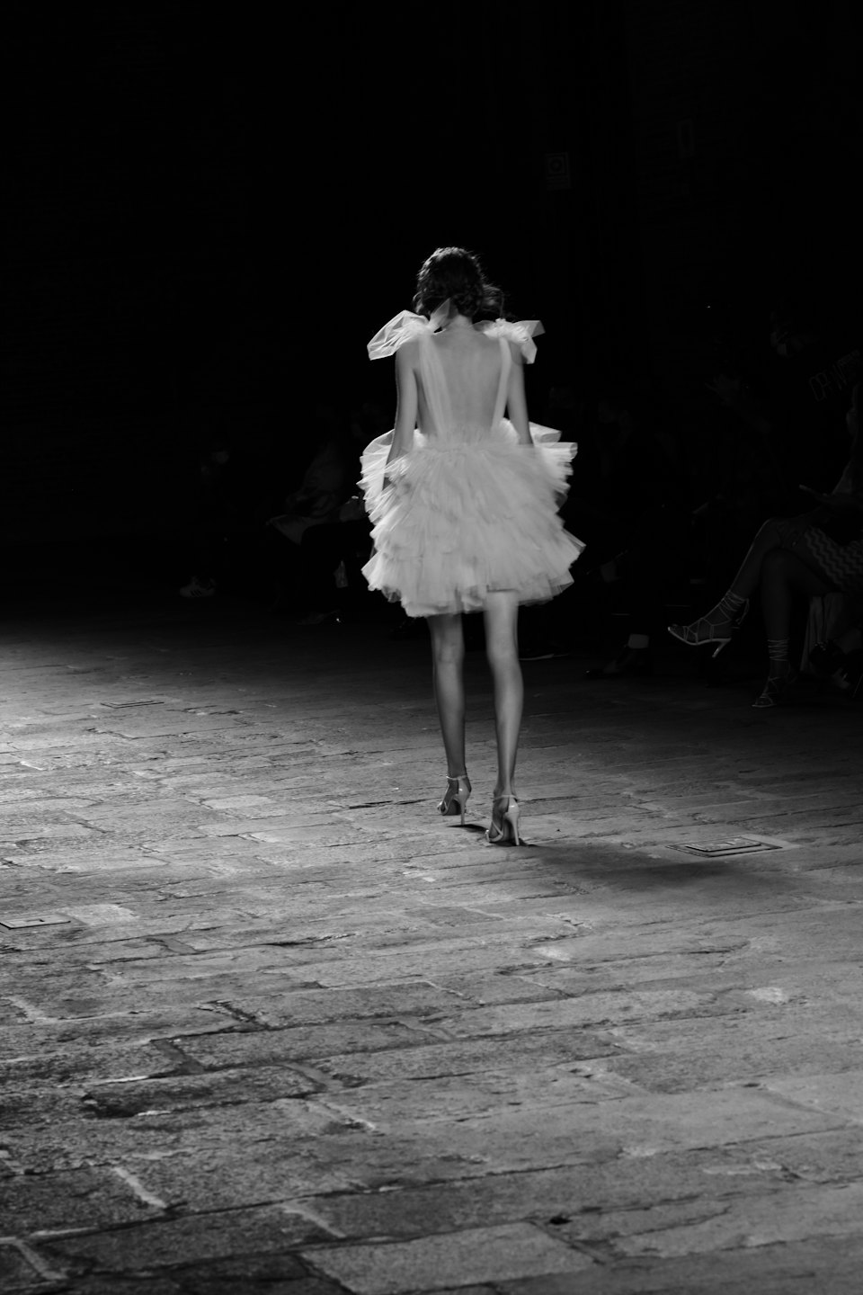 Una modella sfila in passerella con un miniabito a balze.